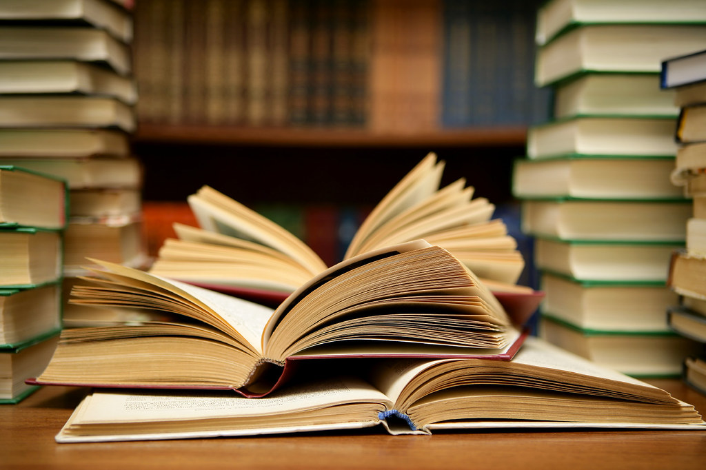 An open book on top of a stack of books.