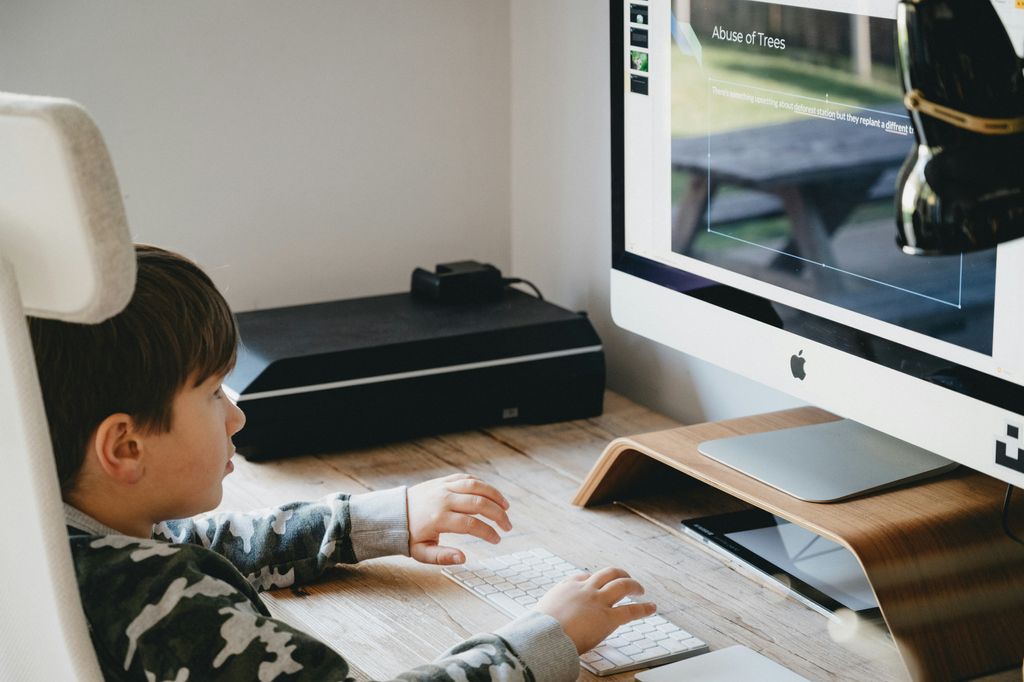 Self-Editing Your Novel -- Refining Character Development and Dialogue --A young boy is sitting at a desk, engrossed in using a computer to self-edit his novel, referring to a checklist.